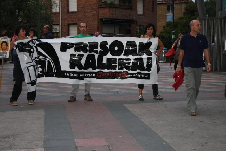 two men walking down the street with a protest banner