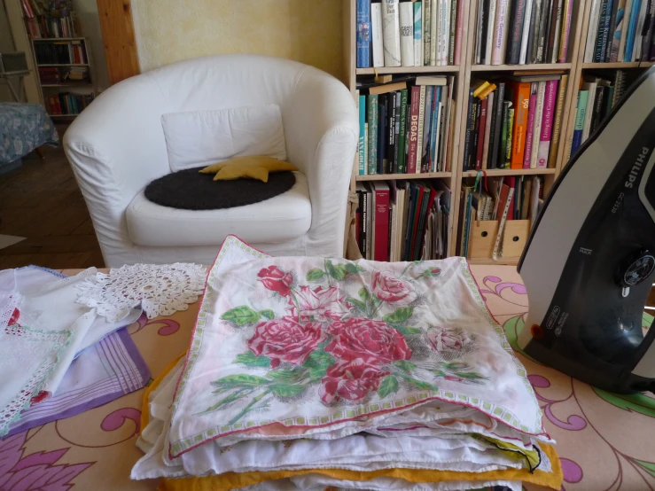 a small white chair and several pillow on a table