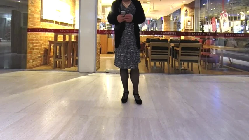 a woman standing on a wooden floor using her cell phone