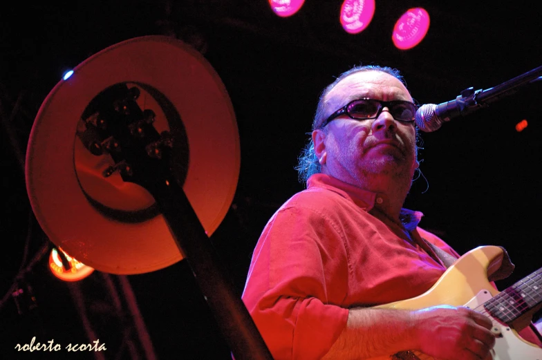 a man is playing guitar while at a microphone