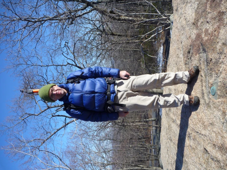a man is standing on a rock wearing a ski hat