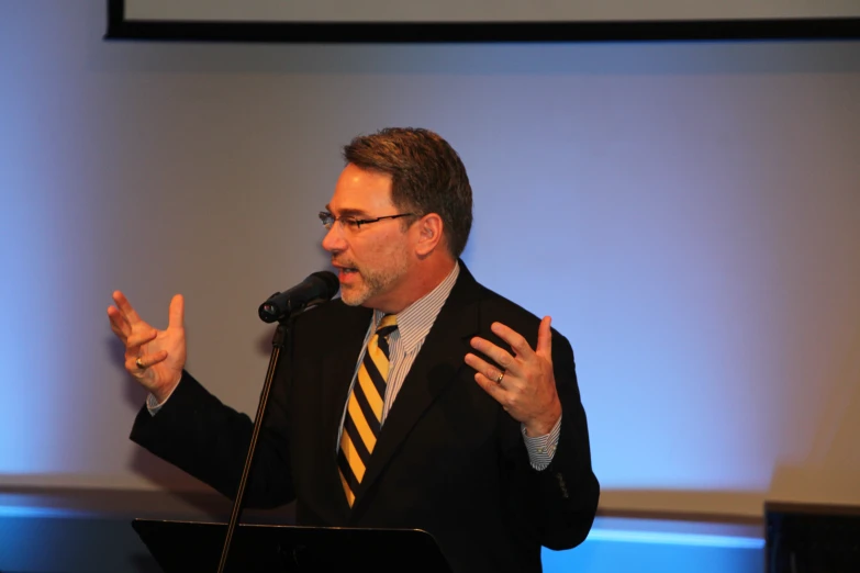 a man standing in front of a microphone making a speech