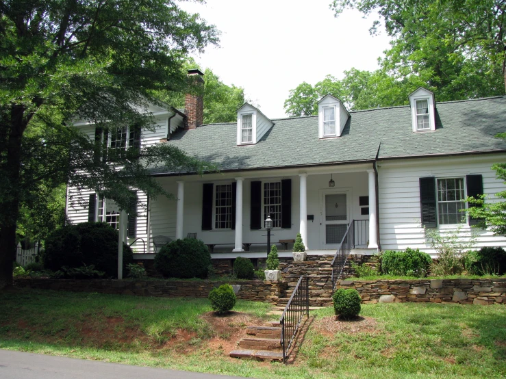 an older country house has white pillars and black shutters