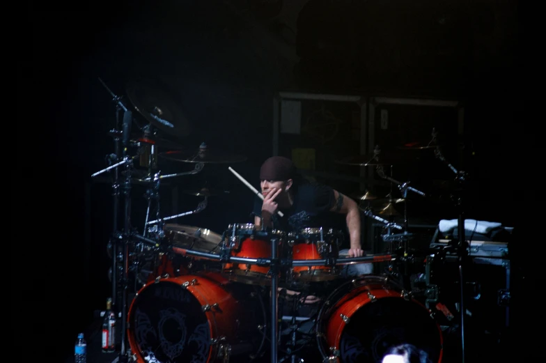 a man playing drums on stage in a dark room