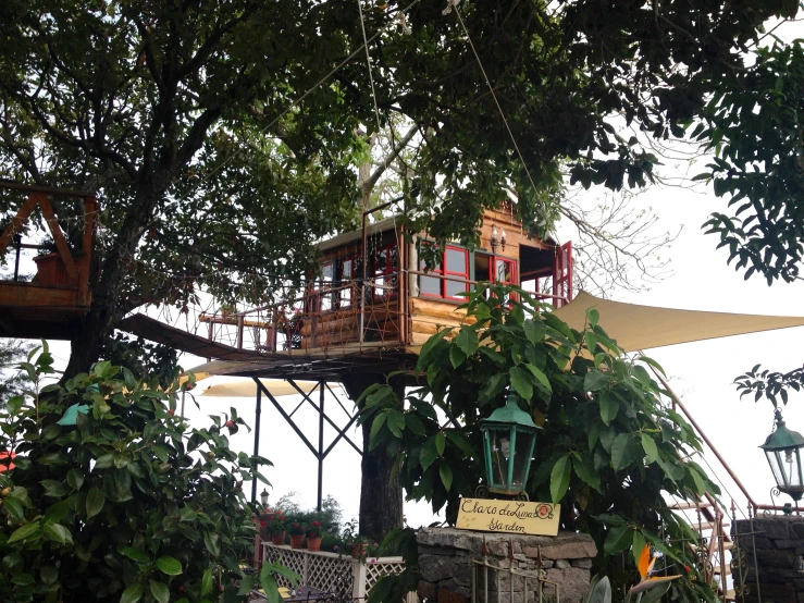 a small tree house with a rope bridge above