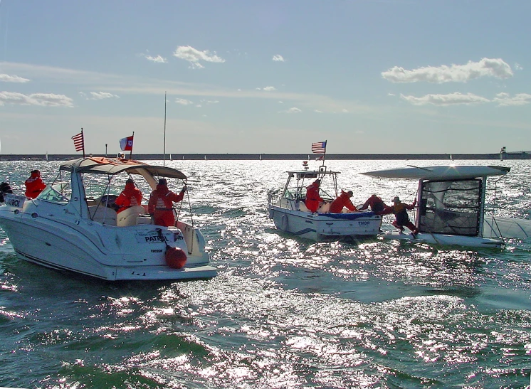 two boats are in the water, as people stand on top