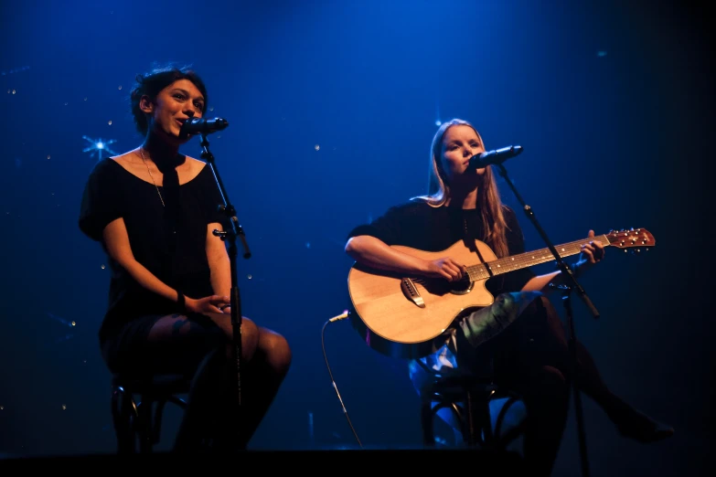 two people that are sitting together with guitar