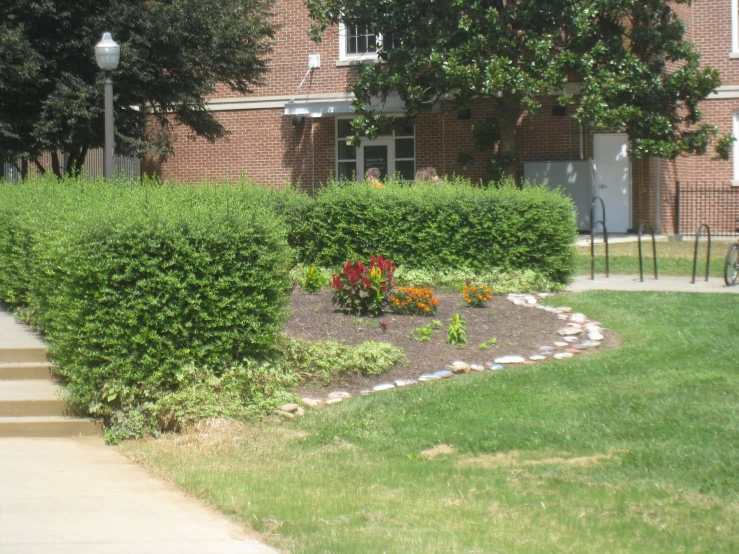 a flower bed in front of a red brick building