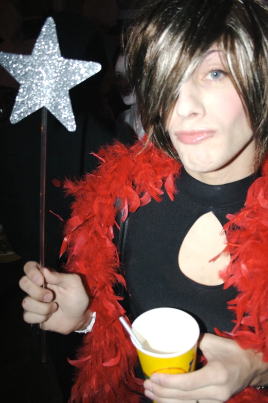 a girl wearing a red feathered coat and holding a drink