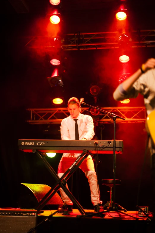 a man standing at a keyboard next to another musical player