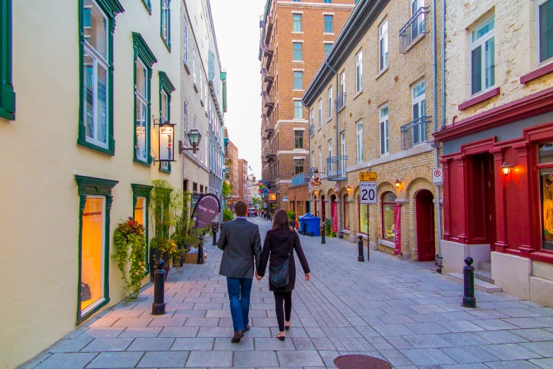 a woman and a man walking down the street in between buildings