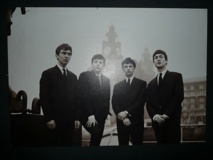 four young men are posed in their suits and ties