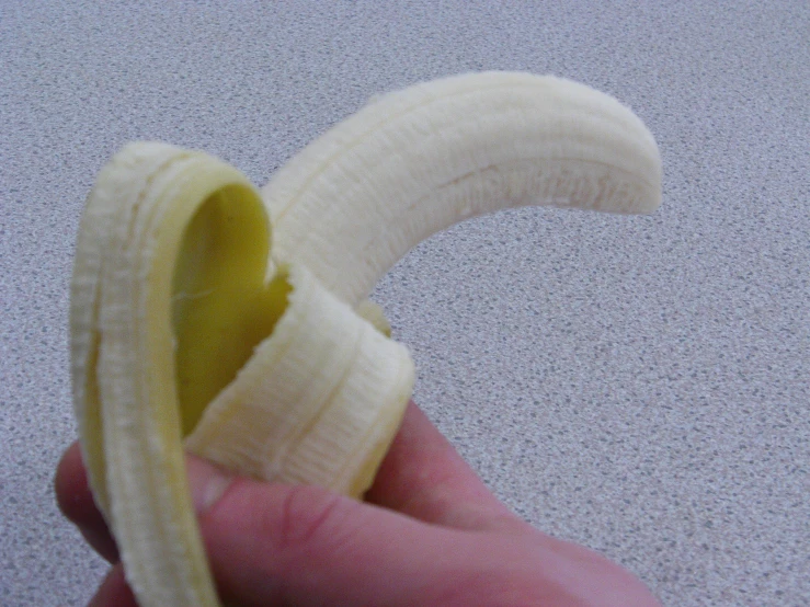a banana peeled with a hand holding one