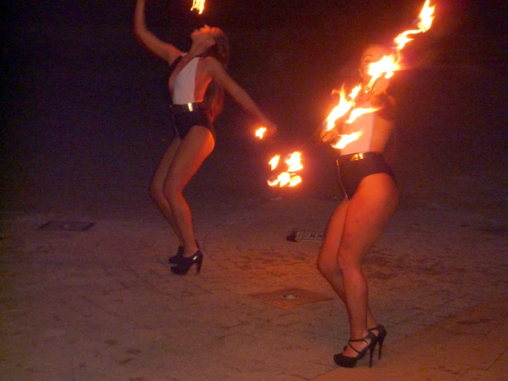 two women stand with torches behind them