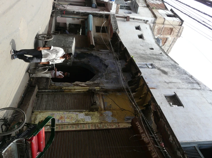 the man walks toward the side of a building that has a bike parked next to it