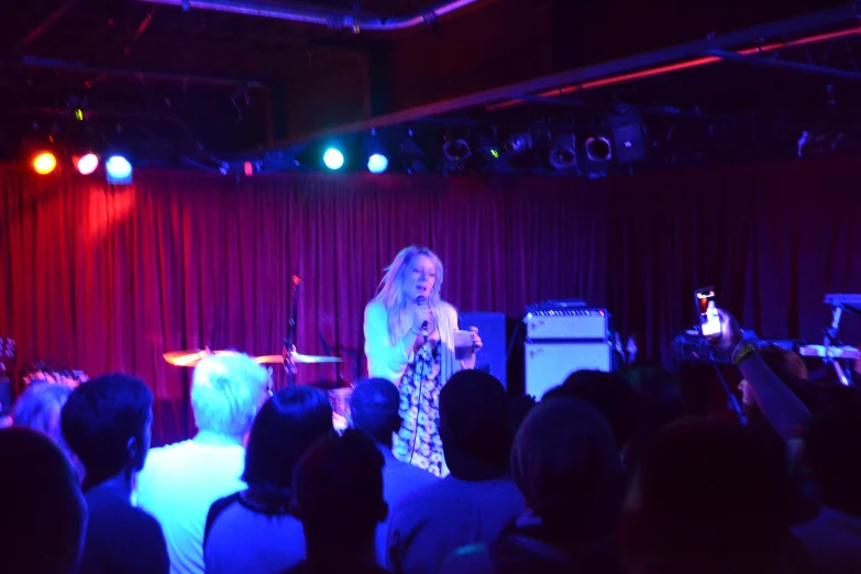 a woman stands on stage and gives a speech