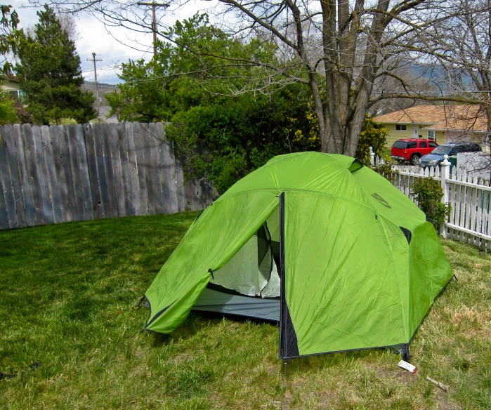 a green tent in the grass with a fence in the background