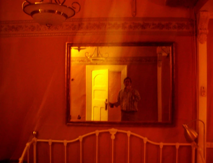 an open doorway is lit by a bright red light while a mirror looks onto the entrance way