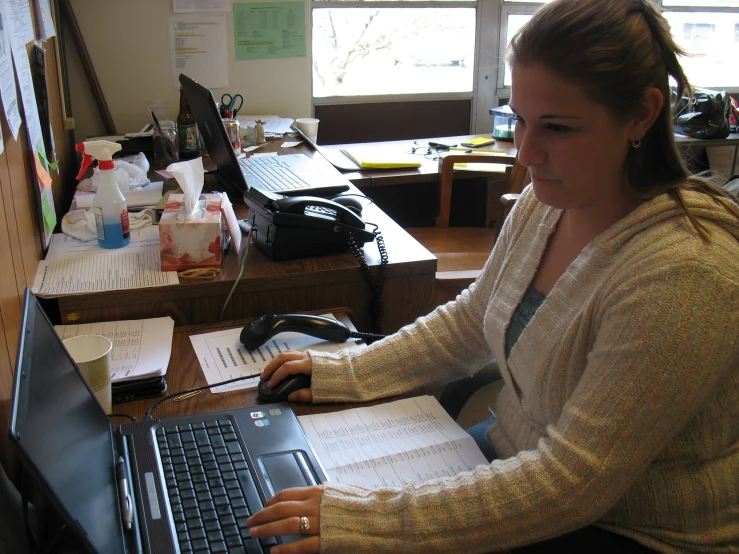 a woman with a notebook in front of a laptop computer