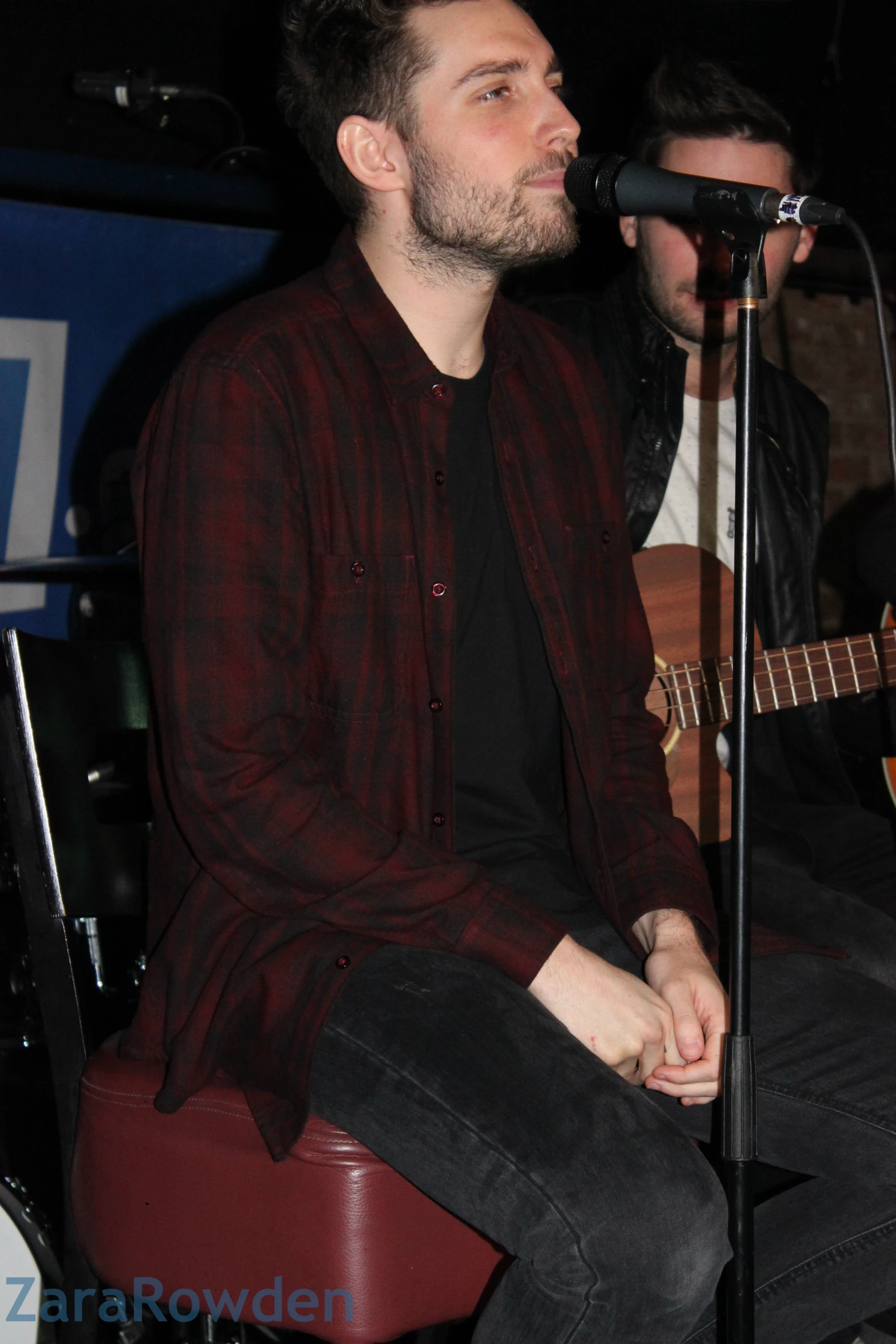 a man in a dark shirt playing guitar and singing into a microphone