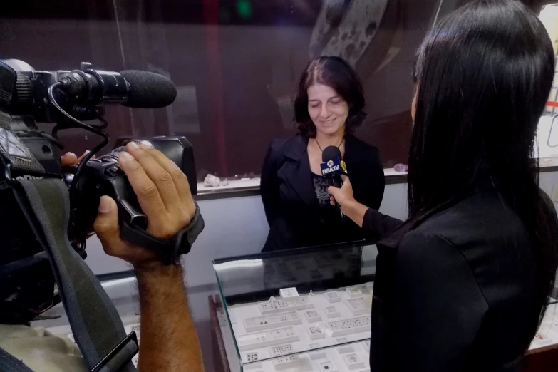 the woman is talking with a reporter in front of a television