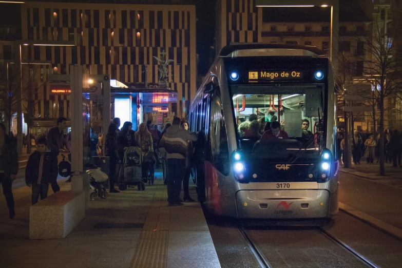 a crowded street with a big bus at night