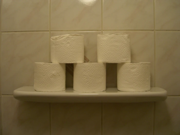 toilet paper rolls stacked on the edge of a roll holder