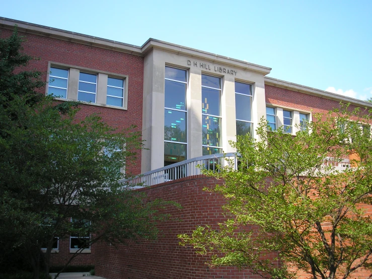 a tall brick building with trees and shrubs