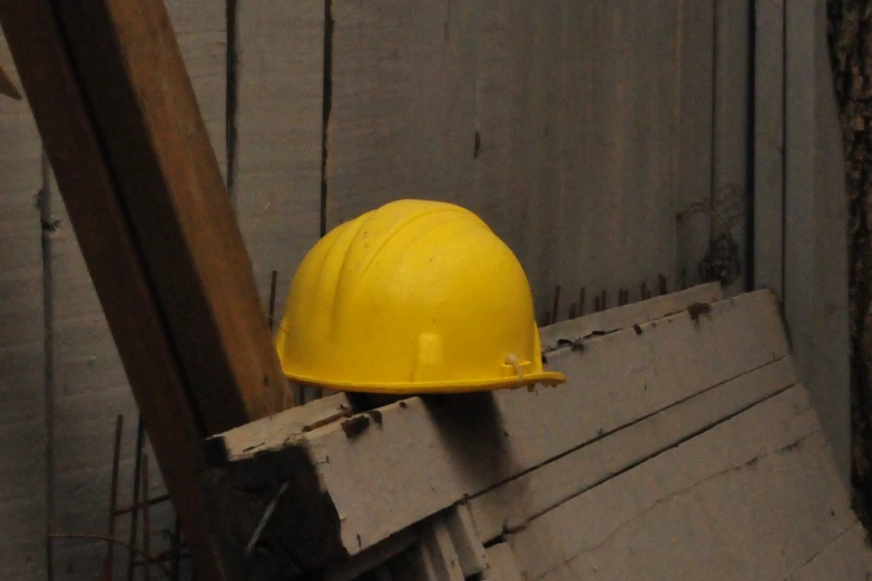 the yellow hard hat is hanging on a piece of wood