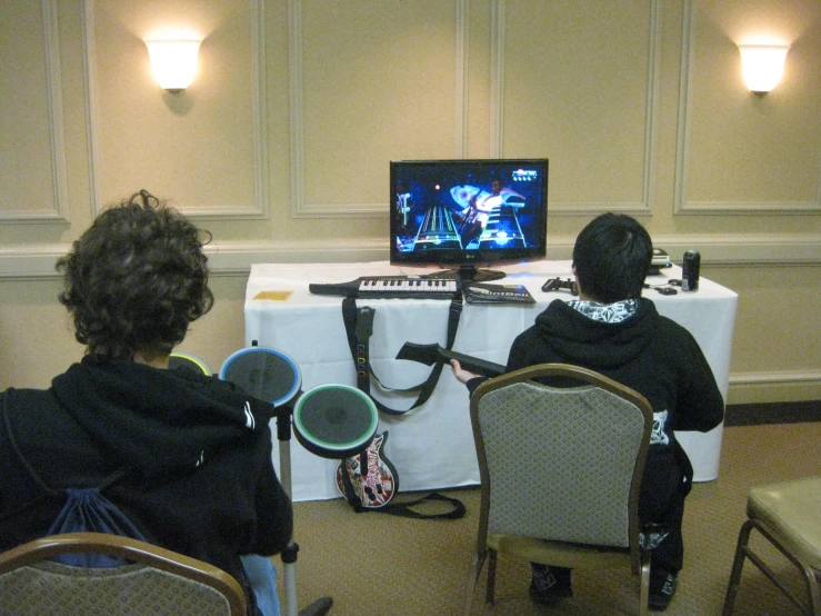 two people sitting at a table with chairs in front of a computer