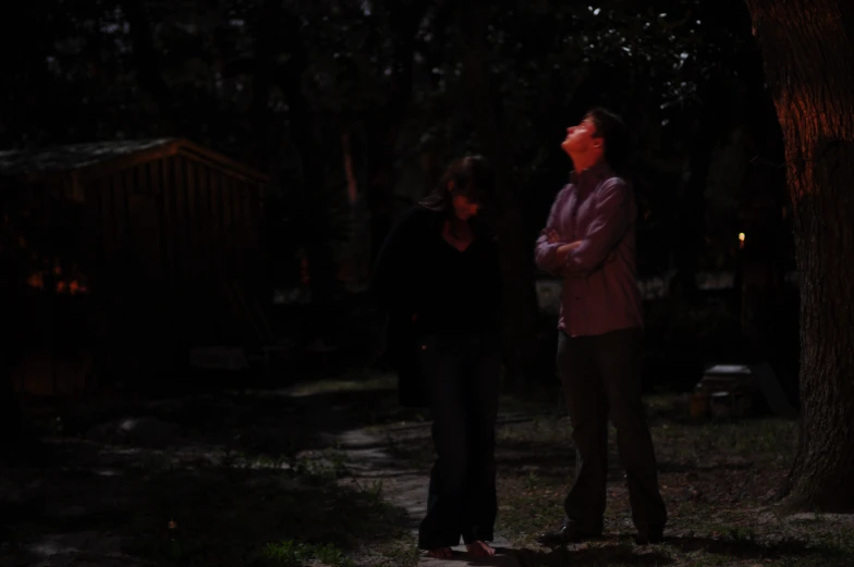 two women standing in the dark under a tree