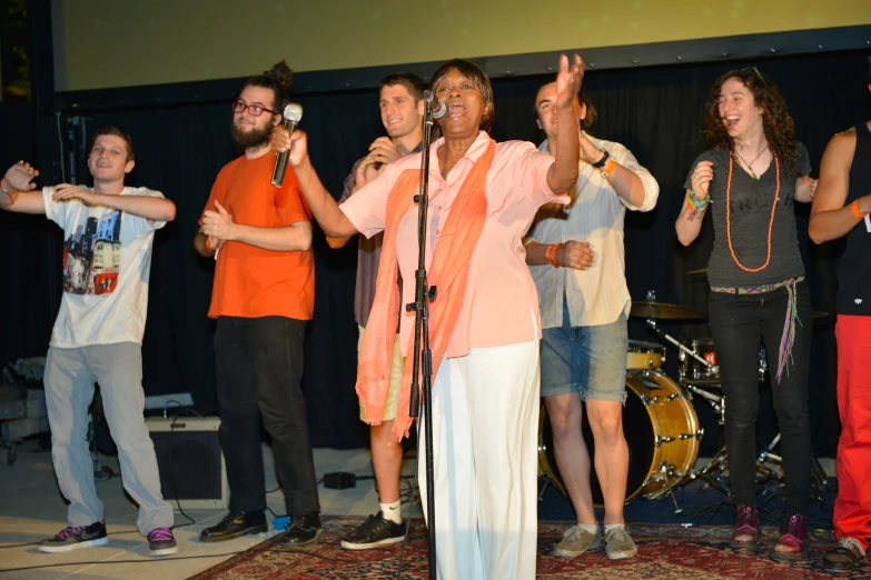 a woman singing into microphones while standing near a crowd of people