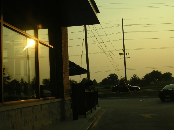 a black car sits outside of a building at sunset