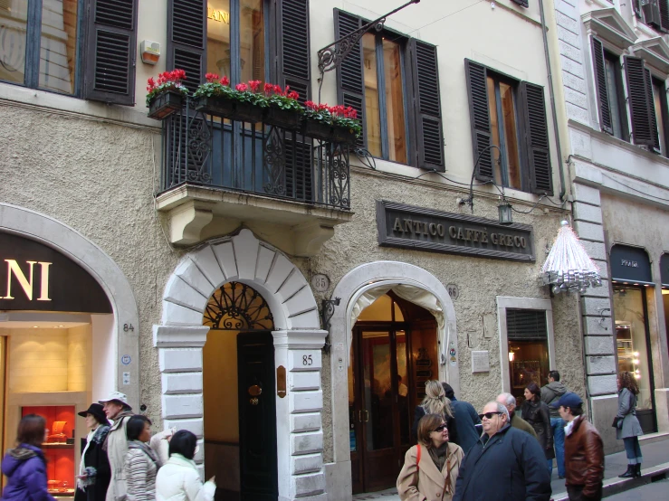 a group of people outside a building with flowers on the balconies