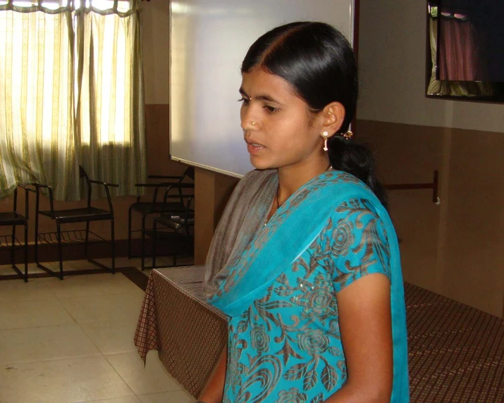 a woman wearing a blue sari and looking at the screen