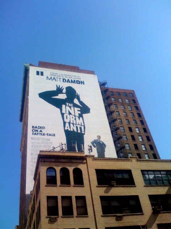 a movie billboard on top of a building with tall buildings in the background