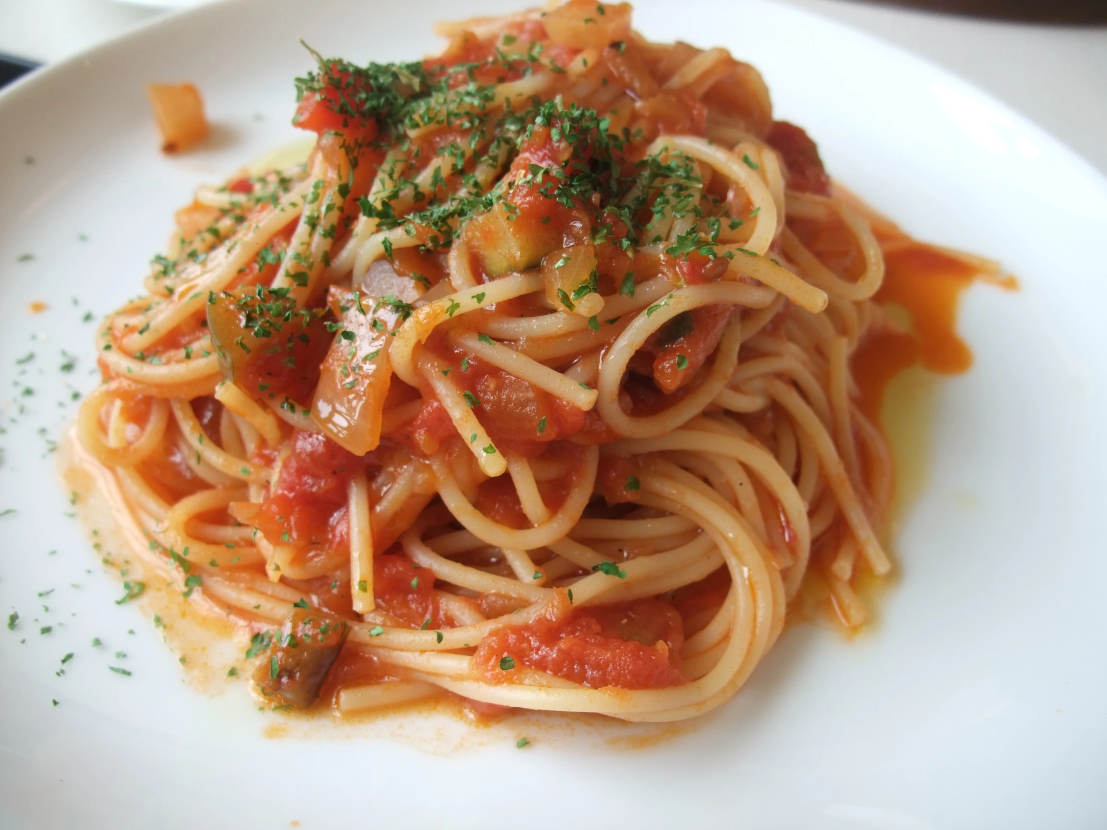 a white plate with spaghetti and sauce covered in parsley