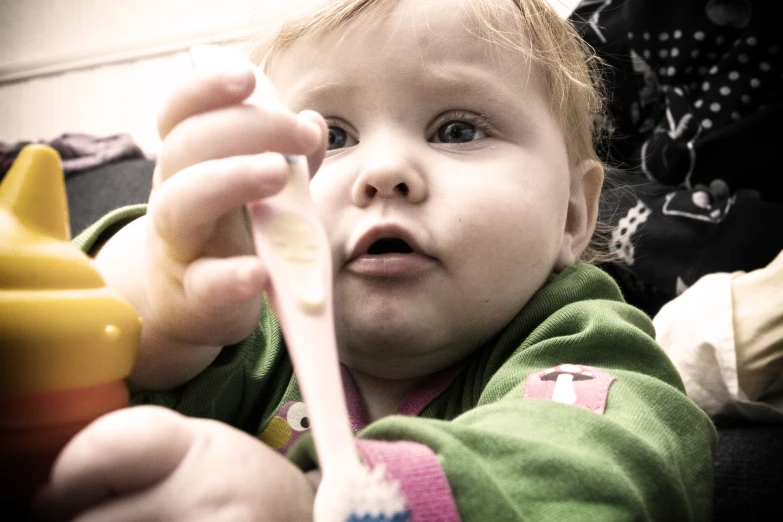 an infant holding onto a yellow tooth brush