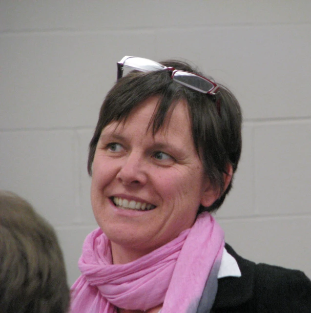 a lady wearing a pink scarf around her neck and some sunglasses on