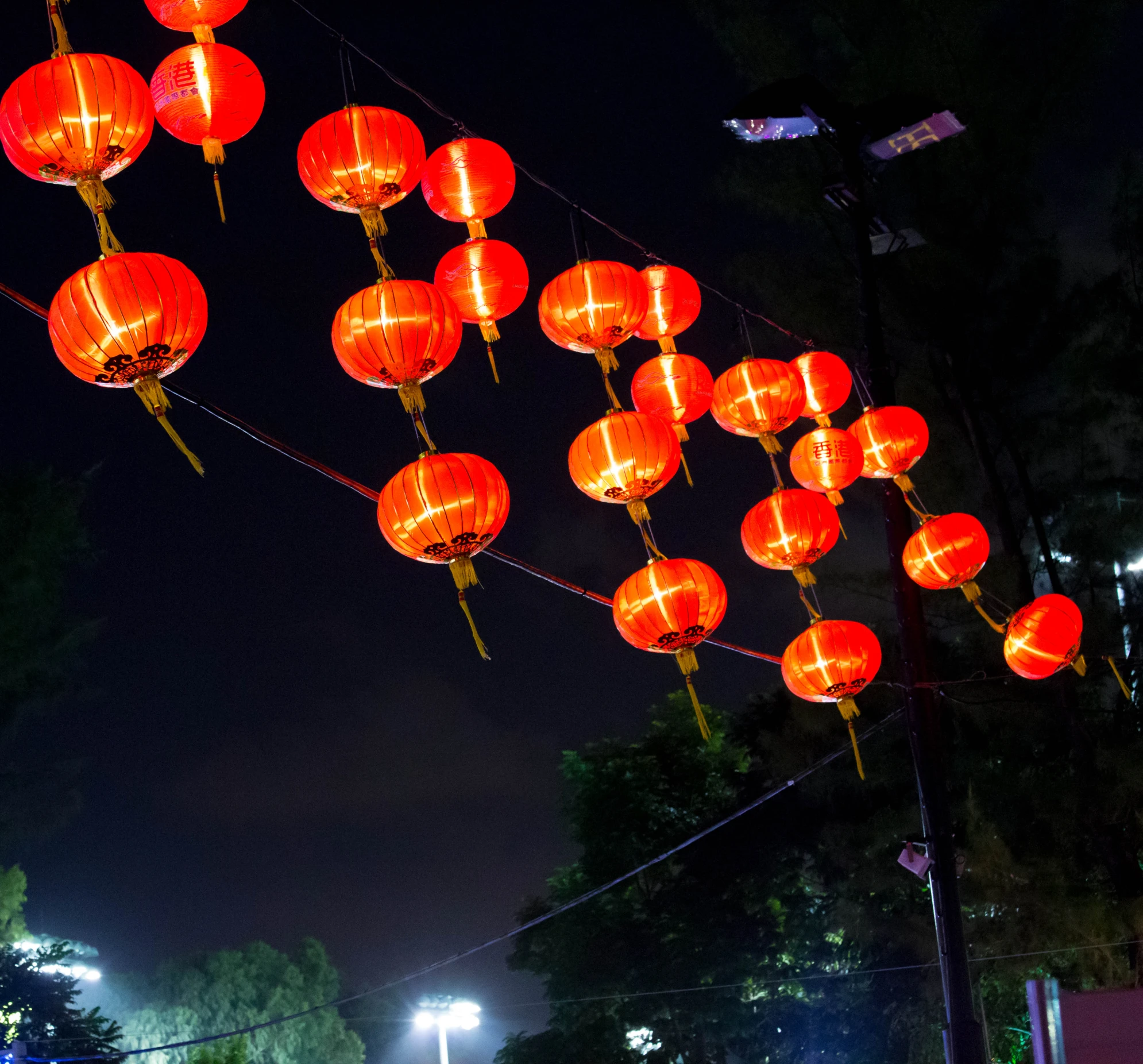 red lanterns line the street at night as people stand on the sidewalk