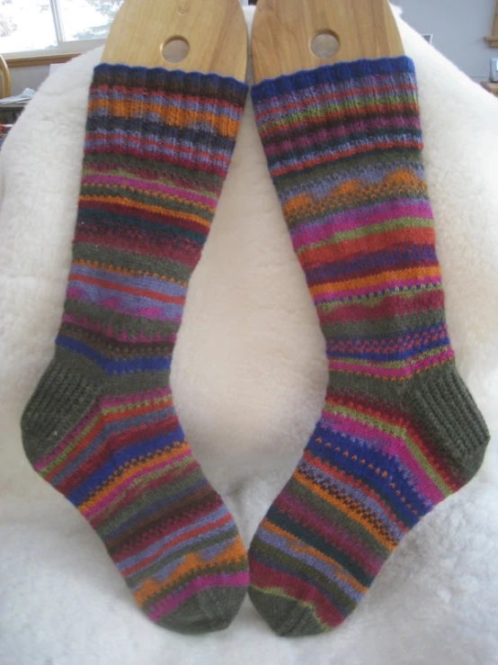 two pairs of colorful knitted socks hang from a rack