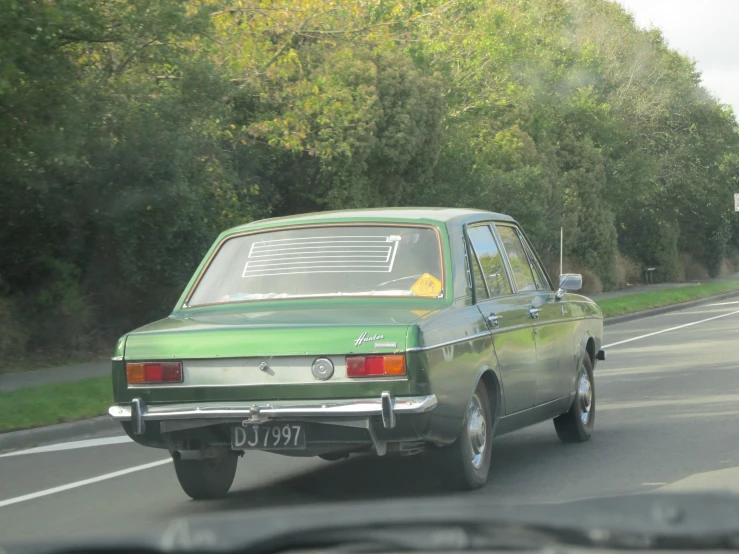 a green station wagon driving down the road