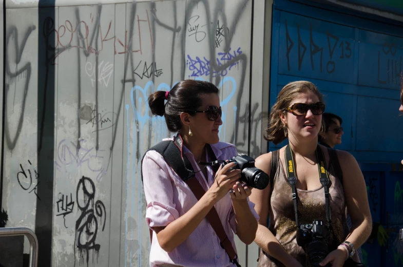 two woman talking to each other as they stand in front of some graffiti