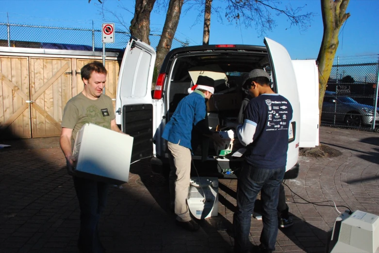 two men are unloading luggage in the back of a van