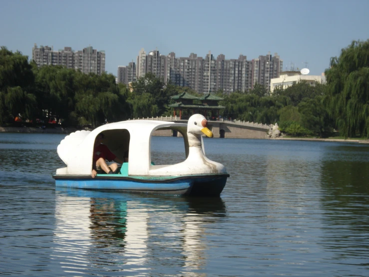 a swan floater floating on the water next to a city