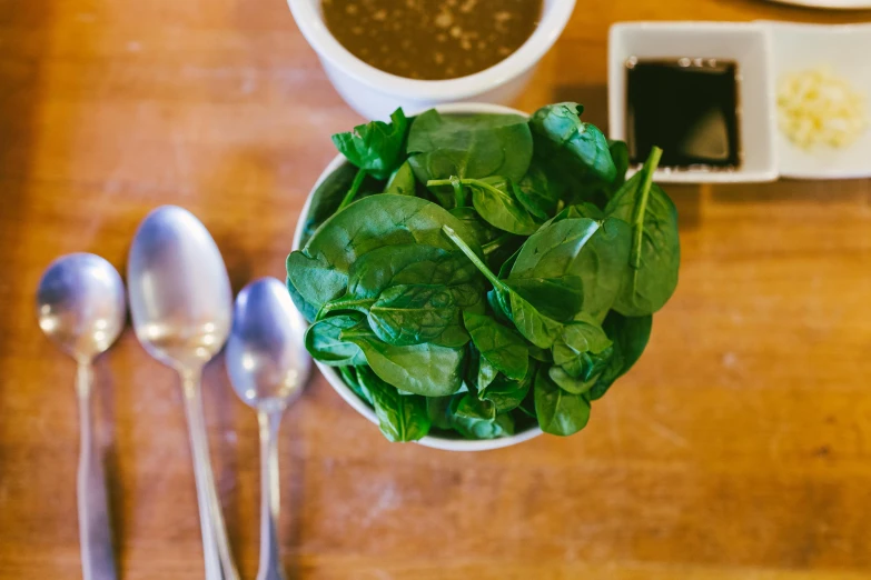 a salad and three spoons sitting on a wooden table