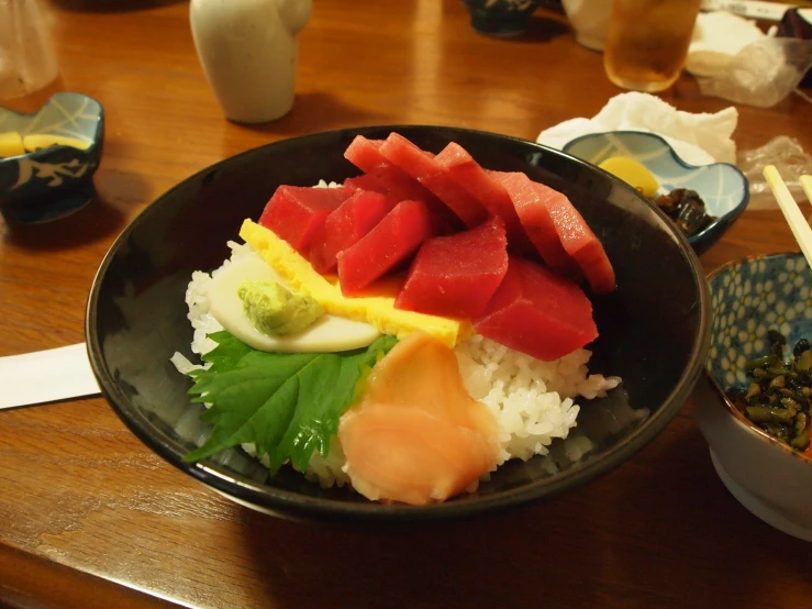 a bowl of sushi with rice, green beans and garnishes