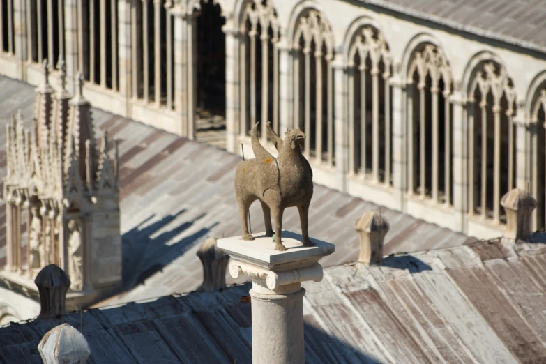 an animal statue sitting on the roof of an old building