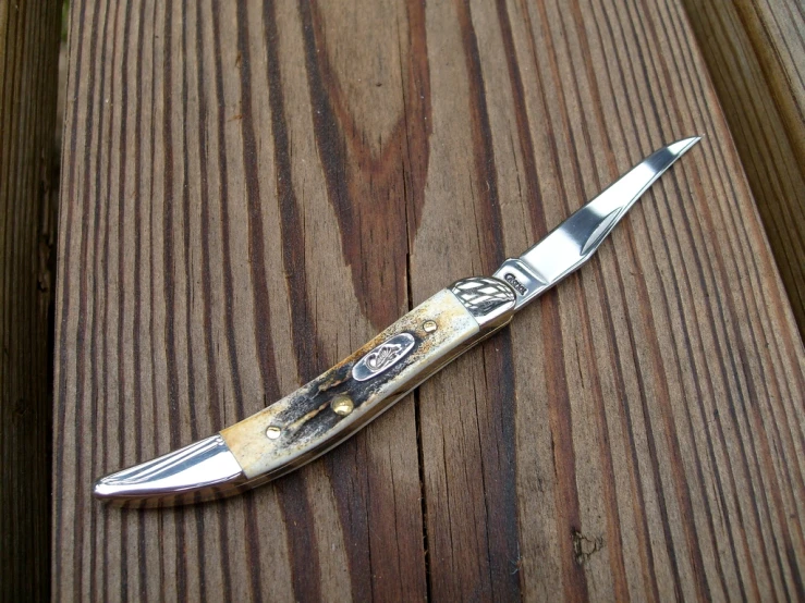 a knife with some writing on it laying on a wooden table