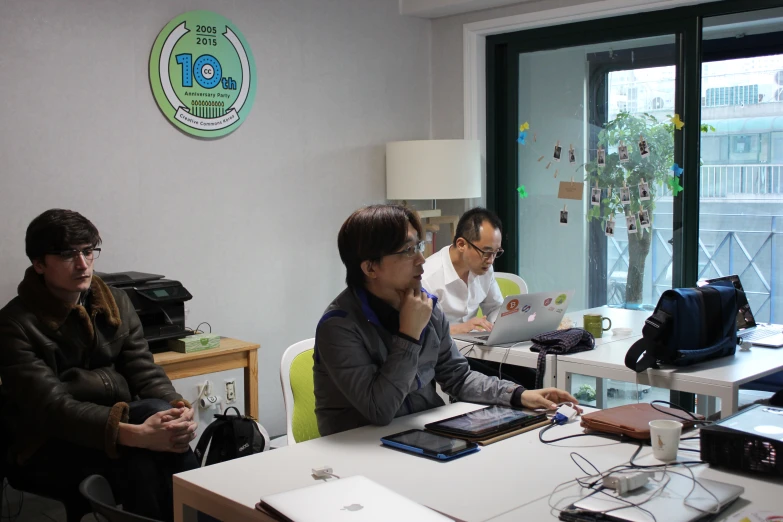 three people sitting around a table working on laptop computers